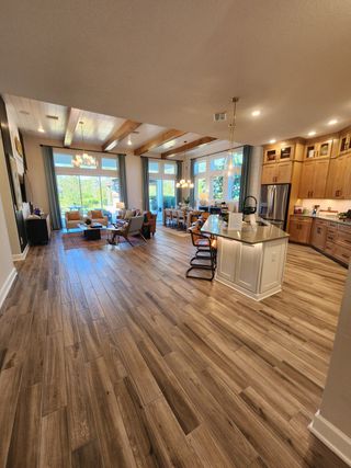 An open-concept living space with wood beam ceilings, a modern kitchen, and expansive windows that flood the room with sunlight.