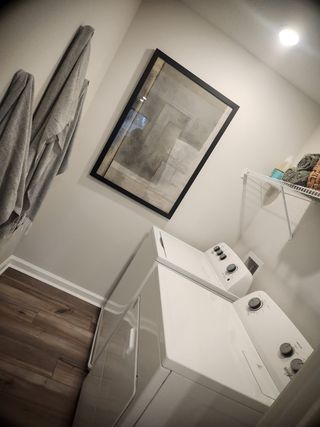 Model Home A sleek laundry room featuring modern appliances, neutral walls, and elegant framed artwork for a touch of sophistication.
