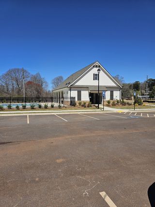 A bright community center with white siding and black shutters, adjacent to a pool and parking lot in Ponderosa Farms by Chafin Communities in Gainesville, GA.