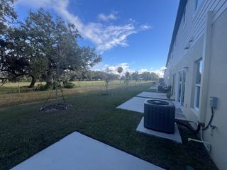 A serene backyard with lush greenery and a concrete pathway at Oak Creek Preserve by Maronda Homes, Lakeland, FL.
