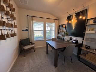 Model Home A cozy office space with decorative shelving, warm lighting, a large window, and a stylish wood desk.