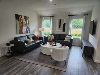 Model Home A cozy living room with dark leather sofas, abstract art, and a circular coffee table on a textured rug.