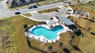 Community Amenities Inviting community pool with surrounding deck and playground in The Colony- Pine Cove by Sitterle Homes (Bastrop, TX).