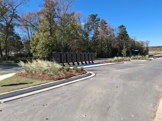 A scenic entrance with mailboxes and lush landscaping in River Falls by Taylor Morrison (Tega Cay, SC).
