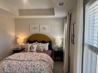 Model Home A charming bedroom with a mustard headboard, floral bedding, and elegant decor accents.