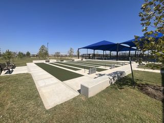 A beautifully designed bocce ball area with multiple lanes, surrounded by benches and covered seating areas, perfect for outdoor fun.
