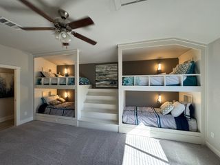 A cozy bedroom featuring custom-built bunk beds with soft lighting and a ceiling fan, ideal for comfort and style.