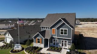 Street view A charming home with wooden shutters and a landscaped yard in Cannon Ranch 40s by Ashton Woods, Dripping Springs, TX.