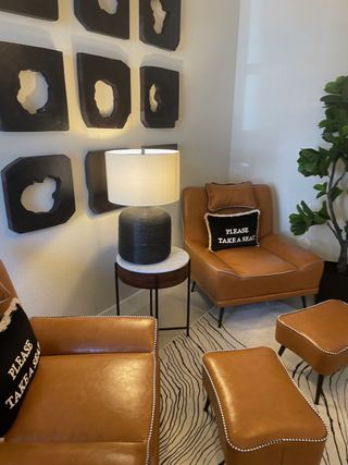 A stylish lounge with caramel leather chairs, black sculptural wall art, and warm lighting.
