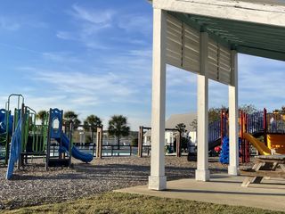 A vibrant community playground with slides and picnic area in Recess Pointe Townhomes by DRB Homes (Moncks Corner, SC).