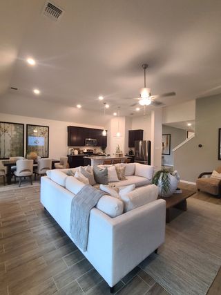 A spacious living area with a cozy sectional, modern kitchen, and elegant dining space, featuring soft lighting throughout.