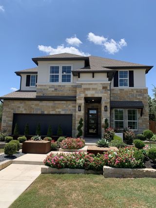 A stunning stone facade home with lush landscaping in Retreat at San Gabriel by Tri Pointe Homes (Georgetown, TX).