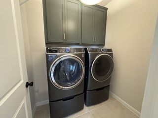 Model Home A modern laundry room with sleek appliances and overhead storage cabinets in neutral tones.