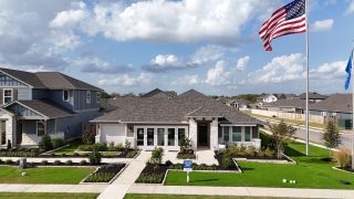 Street view A beautifully designed single-story model home with a manicured lawn and inviting entryway in Riverbend at Double Eagle by Meritage Homes (Cedar Creek, TX).