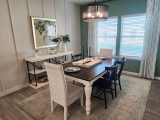 A cozy dining room with a dark wood table, wicker chair, modern lighting, and decorative accents.