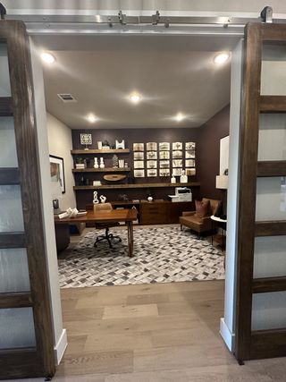 A sophisticated home office with a wooden desk, geometric rug, and decorative shelving for a modern aesthetic.