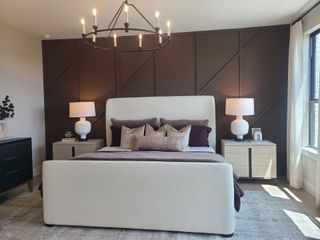 A chic bedroom featuring a plush bed with layered pillows, sleek side tables, and a geometric chandelier.