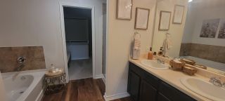 Model Home A bathroom with dual vanities, dark wood cabinets, and a separate tub and shower area offers a functional and stylish space.