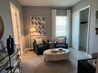Model Home A cozy sitting area with plush chairs, soft lighting, and modern decor in a serene, gray-toned room.
