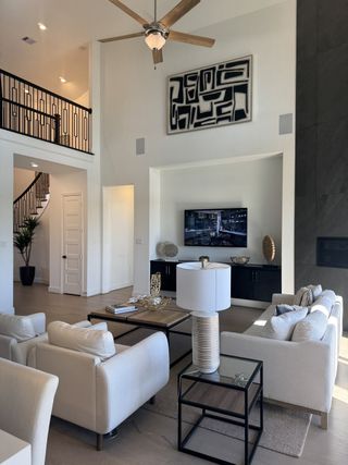 A contemporary living room featuring a high ceiling, modern art, cozy seating, and a sleek TV area.
