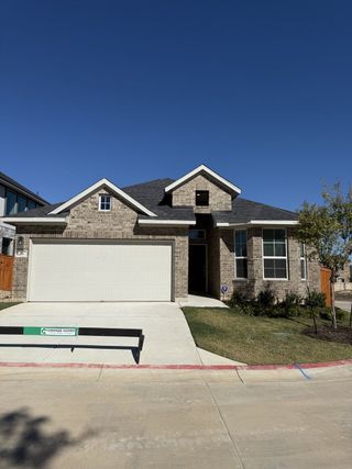 Charming brick home with spacious garage in Deerbrooke Cottages by Chesmar Homes, Leander, TX.
