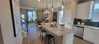 An open-concept kitchen and living area with granite countertops, modern lighting, and cozy seating.