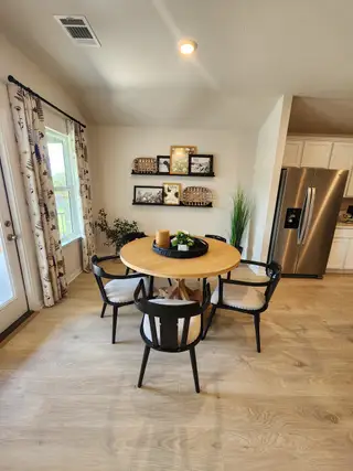A cozy dining nook with a round wooden table, black chairs, and stylish wall decor.