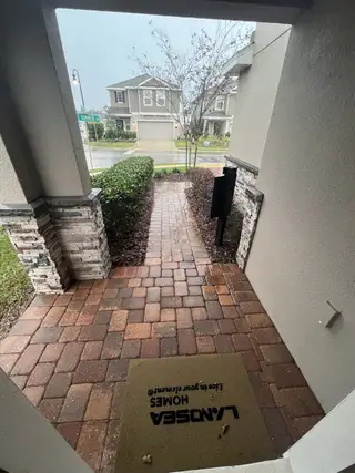 A welcoming porch with brick pathway and stone accents, situated in Horse Creek at Crosswinds by Landsea Homes (Davenport, FL).