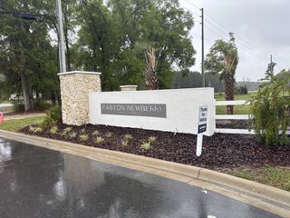 A welcoming entrance with a stylish stone sign and lush landscaping in Avalon Woods by D.R. Horton (Newberry, FL).