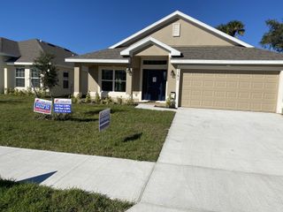 A charming beige home with a manicured lawn in Hickory Ridge by Adams Homes, Cocoa, FL.
