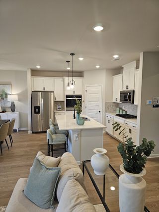 A modern kitchen with sleek white cabinetry, stainless steel appliances, and a cozy seating area, offering a welcoming ambiance.