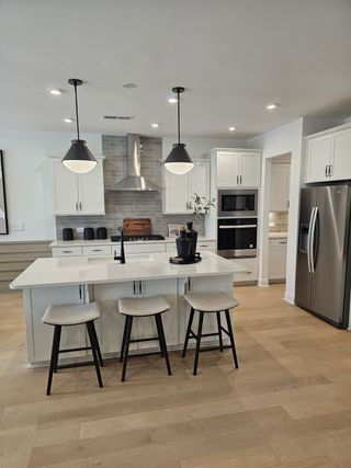 A modern kitchen with a sleek island, pendant lights, stainless steel appliances, and elegant cabinetry.