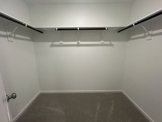 A spacious walk-in closet with shelving and neutral carpet, perfect for organizing and maximizing storage.