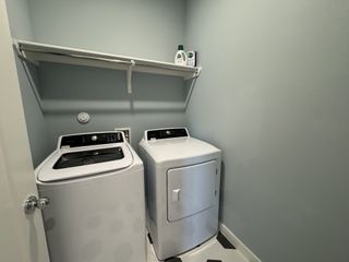 A modern laundry room featuring a sleek washer and dryer, with soft blue walls and practical shelving.