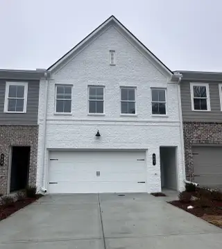 A modern white brick townhouse with chic curb appeal in River Walk Place by Traton Homes (Lawrenceville, GA).