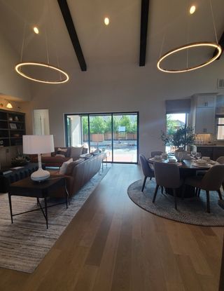 A contemporary living and dining space with chic lighting, elegant furnishings, and expansive glass doors opening to a serene patio.
