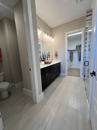 Model Home A modern bathroom featuring a dark vanity, spacious mirror, and elegant lighting fixtures.