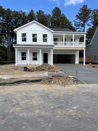 A modern white home under construction in Watson Hill by Ashton Woods (Summerville, SC), set against a backdrop of lush trees.