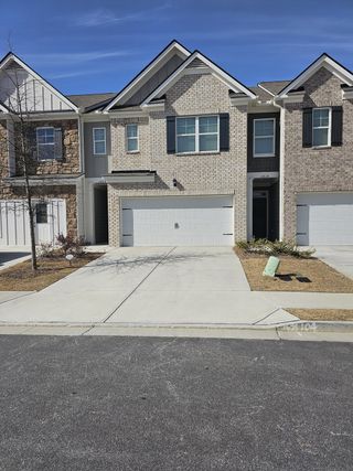 Model Home Charming brick townhomes with modern black shutters and two-car garages in Greyton Springs Place by D.R. Horton (Buford, GA).