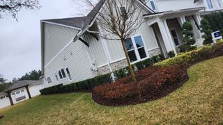 A charming farmhouse-style home in SilverLeaf by Lennar, featuring stone accents, lush landscaping, and a welcoming front porch.