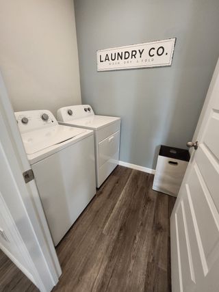 A functional laundry room with a sleek washer and dryer set, wood flooring, and a stylish "Laundry Co." wall sign.