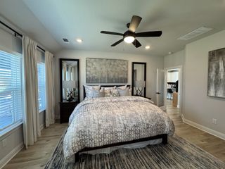 A cozy bedroom featuring a plush bed with patterned bedding, elegant mirrors, and natural light from large windows.