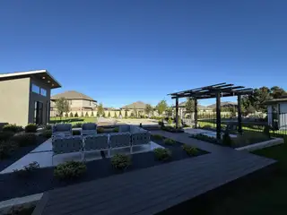 Chic outdoor seating area with pergola in Santa Rita Ranch by Scott Felder Homes, surrounded by lush landscaping in Liberty Hill, TX.