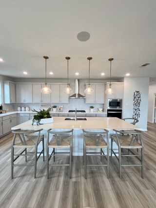 Model Home A modern kitchen with a large island, elegant pendant lighting, and sleek cabinetry, offering a bright and inviting space.