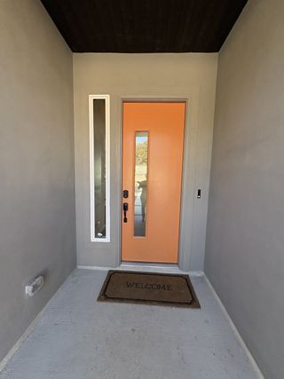 A stylish modern home with a bright orange front door in Esperanza by Scott Felder Homes (Boerne, TX).