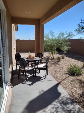 A cozy patio with elegant outdoor seating, overlooking a low-maintenance desert yard and clear blue skies.