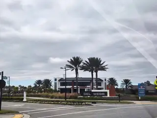 A modern community entrance with palm trees and a sleek clubhouse welcomes you to Del Webb eTown by Del Webb (Jacksonville, FL).