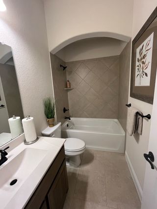 Elegant bathroom with a tiled bathtub, arched niche, modern fixtures, and a sleek vanity for a stylish look.