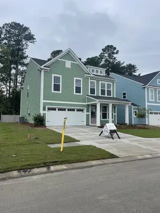 A charming green house with a spacious driveway in Homecoming by True Homes (Ravenel, SC).