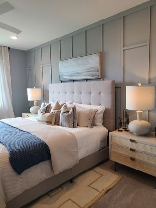 Model Home A chic bedroom featuring a tufted headboard, layered textiles, and soft lighting for a cozy, inviting atmosphere.